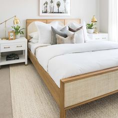 a bed with white sheets and pillows in a bedroom