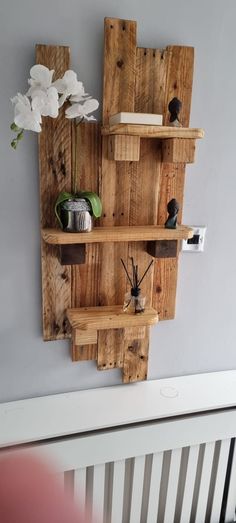 a wall shelf made out of wooden pallets with flowers on top and candles in the bottom