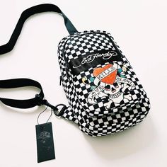 DEADSTOCK. NEW WITH TAGS. ED HARDY BAG / ED HARDY FESTIVAL BAG / ED HARDY SHOULDER BAG  Incredible black and white checkboard checkered print Ed Hardy crossover bag / crossbody bag / shoulder bag / festival bag. Ed Hardy Love Kills Slowly graphic branding on front. One small front zip pocket compartment with a large zip main compartment.  Length 12 inches - width 9 inches. Big enough to fit all essentials. Purse, wallet, phone etc. Black adjustable strap. Can be worn across body, or as a shoulde Trendy Chest Bag With Mobile Phone Pocket, Trendy Satchel Chest Bag With Mobile Phone Holder, Trendy School Shoulder Chest Bag, Trendy Chest Bag With Mobile Phone Holder, Trendy Shoulder Chest Bag For Mobile Phone, Trendy School Chest Bag With Removable Pouch, Trendy Crossbody Bags For Streetwear, School Crossbody Chest Bag With Mobile Phone Pocket, Trendy Chest Bag With Cell Phone Pocket For School