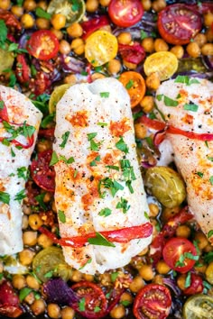 three fish fillets with tomatoes, peppers and chickpeas on a platter