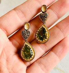 A beautiful vintage pair of drop earrings made of 9K yellow gold and silver set in three parts. On the top two oval-shaped studs, in the middle two hearts covered with rose-cut natural brown diamonds, and on the bottom two artificial green stones in teardrop shape. A lovely pair of earrings with a slight dangle.  In this pair of earrings, the brown diamonds are natural in rose cut and the green stones are synthetic yet very impressive.  Artificial gemstones are popular in jewelry manufacture sin Vintage Gold Gemstone Earrings, Ornate Gold Earrings With Diamond Accents, Vintage Teardrop Gemstone Earrings, Ornate Gold Earrings With Rose Cut Diamonds, Elegant Handmade Pear-shaped Earrings, Antique Gold Pear-shaped Jewelry, Antique Pear-shaped Gold Jewelry, Gold Pear-shaped Jewelry With Rose Cut Diamonds, Pear-shaped Gold Jewelry With Rose Cut Diamonds