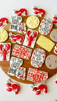 some decorated cookies are on a wooden platter with red and white icing in the shape of lobsters