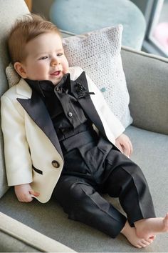 a young boy in a tuxedo sitting on a couch