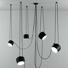 several black lamps hanging from the ceiling in a room with grey walls and flooring