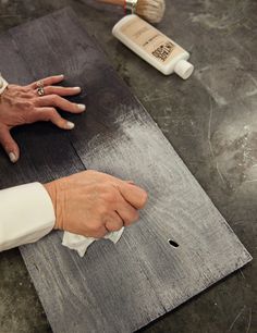 a woman is peeling something off of a piece of wood with her hands on it