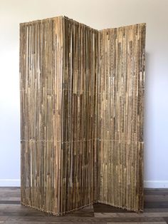 a room divider made out of bamboo sticks on the floor in front of a wall