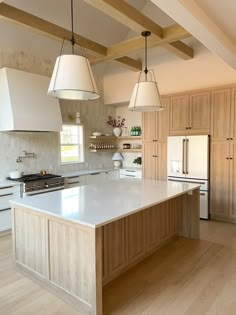 a large kitchen with an island in the middle and two pendant lights hanging from the ceiling