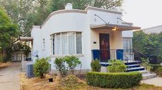 a white house with blue shutters on the front and stairs leading up to it