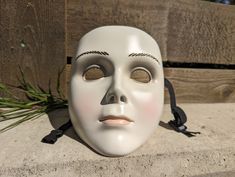 a white mask sitting on top of a wooden fence