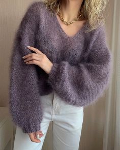 a woman wearing a purple sweater and white pants