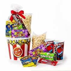 three buckets filled with different types of candy and snacks next to each other on a white surface