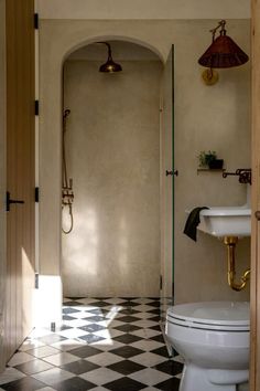 a white toilet sitting in a bathroom next to a walk in shower and black and white checkered floor