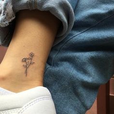 a woman's foot with a small flower tattoo on her left side ribcage