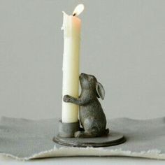 a candle that is sitting next to a small bunny figurine on a table