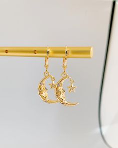 Radiate celestial elegance with The Moon Goddess Huggie Earrings. These earrings capture the allure of lunar beauty in a mesmerizing design. Meticulously crafted, the mini moon and goddess charms exude a sense of ethereal grace and power. The huggie style ensures a secure fit, promising comfort throughout the day. Whether you're drawn to cosmic mystique or seek unique accessories, these earrings make a statement. Perfect for both casual outings and special occasions, they infuse your ensemble wi Mystical Gold Moon Phase Earrings, Half Moon Earrings With Moon Charm, Metal Half Moon Earrings With Moon Charm, Half Moon Metal Earrings With Moon Charm, Celestial Moon Phase Earrings, Half-moon Metal Earrings With Moon Charm, Celestial Moon Phase Moon Earrings, Gold Crescent Earrings With Moon Phase Detail, Gold Dangle Earrings With Moon Phase Detail