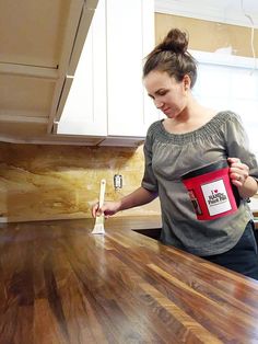 a woman is holding a paint roller in her hand while standing at the kitchen counter