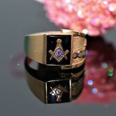 A gentleman's 10 karat yellow gold Masonic ring with a 10 millimeter by 8 millimeter rectangular black onyx and 2 symbols on one side.  This ring is size 10 Black Symbolic Hallmarked Signet Ring, Symbolic Black 14k Gold Jewelry, Black Symbolic Signet Ring With Polished Finish, Masonic Ring, Estate Jewelry, Black Onyx, Onyx, Size 10, Yellow Gold