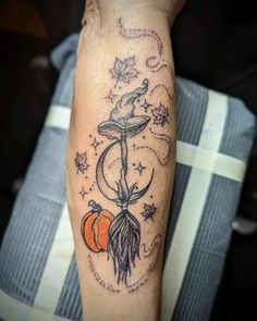 a person with a tattoo on their arm holding an orange and a crescent in the sky