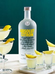 a bottle of absolut citron next to three glasses with lemon wedges