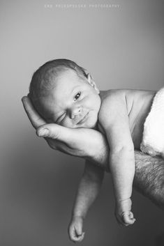 a black and white photo of a baby being held by someone's hand in the air