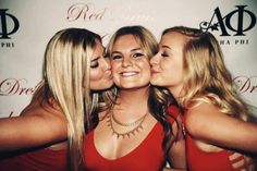 three beautiful young women kissing each other in front of a red carpet