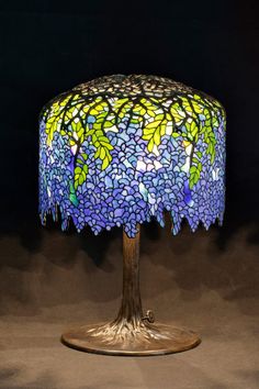 a lamp that is sitting on top of a wooden base with blue and yellow flowers