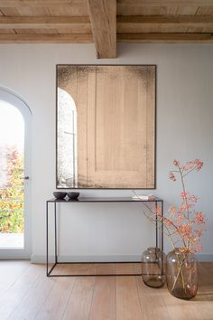 a mirror sitting on top of a table next to vases