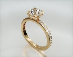 a gold engagement ring with diamonds on the band and a center stone in the middle