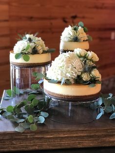 three cakes with white flowers and greenery on top