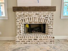 a brick fireplace in a room with two windows