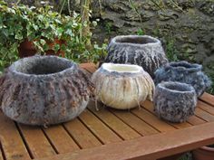 four vases sitting on top of a wooden table next to potted planters