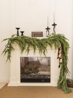 a fireplace decorated with evergreen and candles