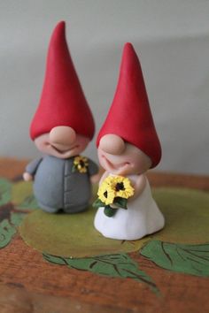 two little gnomes are standing next to each other with flowers in their hands and one is holding a sunflower