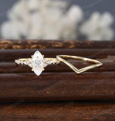 an engagement ring with a pear shaped diamond in the center on top of a wooden stand