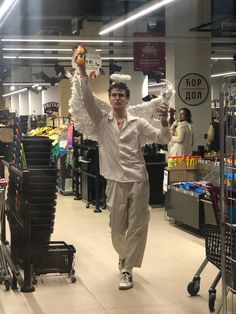 a man in white shirt and pants holding up a stuffed animal at the end of a shopping mall