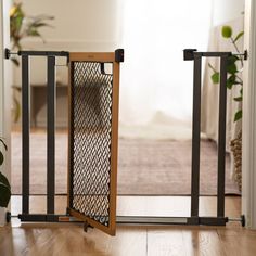 an open gate on the floor in front of a living room with a couch and potted plant