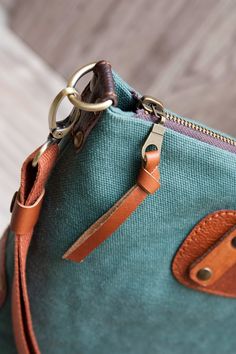 a green purse with brown leather handles