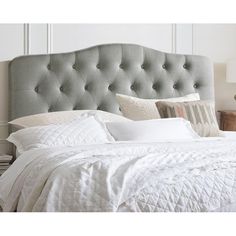 a bed with white linens and pillows on it's headboard in a bedroom