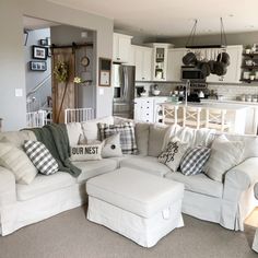 a living room filled with white furniture and lots of pillows on top of it's couches