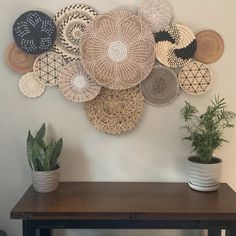 a table with some potted plants on top of it next to a wall mounted wicker basket