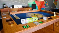 a wooden table with cards and dices on it in front of a colorful wall