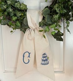 a white door with a wreath and two monogrammed towels hanging on it's side