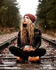 a woman is sitting on the train tracks