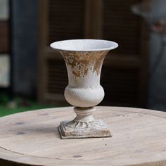 a white vase sitting on top of a wooden table