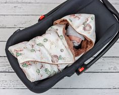 a baby wrapped in a blanket is sitting in a stroller on a white wooden floor