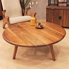 a wooden coffee table sitting on top of a hard wood floor next to a white chair