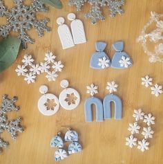 snowflakes, earrings and other decorations on a table with silver glittered leaves