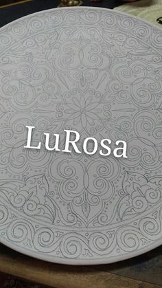 the word lurosa written in white on a gray plate with swirls and scrolls