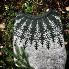 a sweater with trees on it sitting in the grass