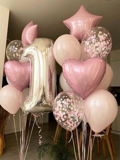 pink and white balloons are arranged in the shape of a number one, with confetti sprinkles on them